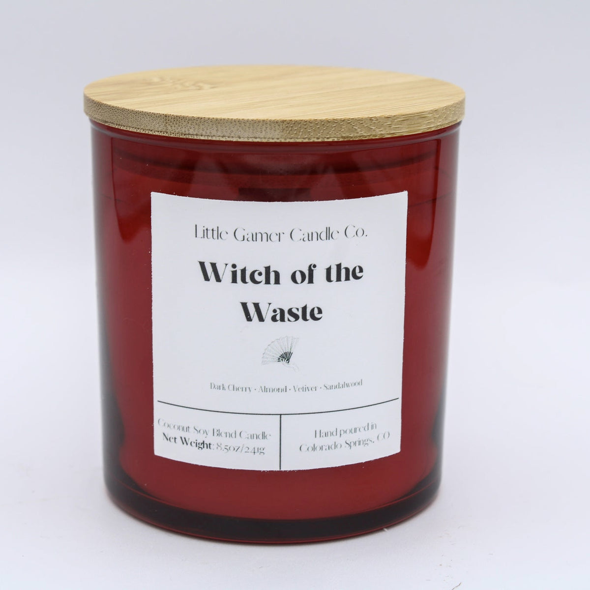A red glass jar candle with a light wood lid and a white label reading 'Little Gamer Candle Co. Witch of the Waste' on a white background.