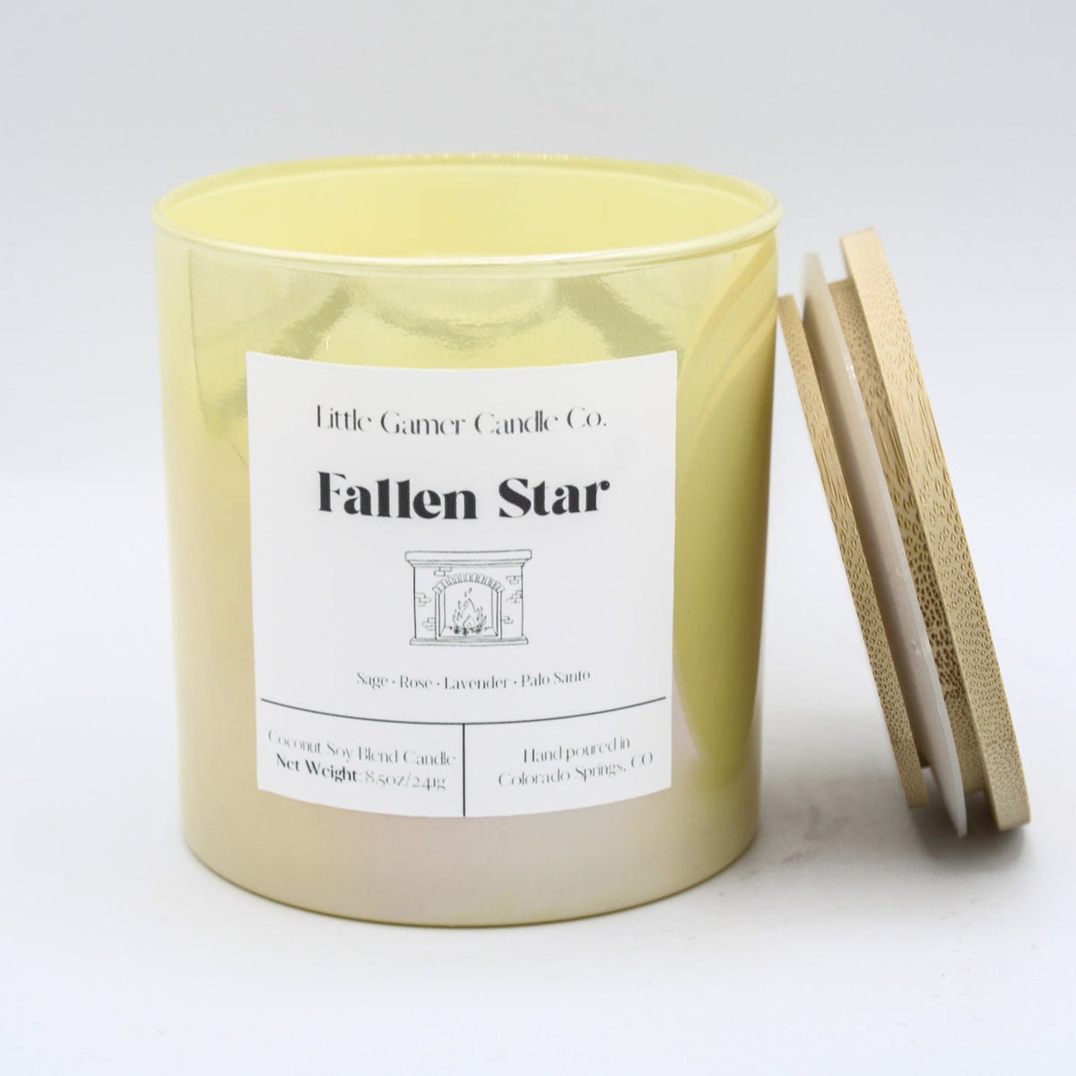 A yellow soy wax candle in a cylindrical glass jar with a white label reading 'Little Candles Candle Co. Fallen Star,' shown with a wooden lid leaning against the jar on a white background.